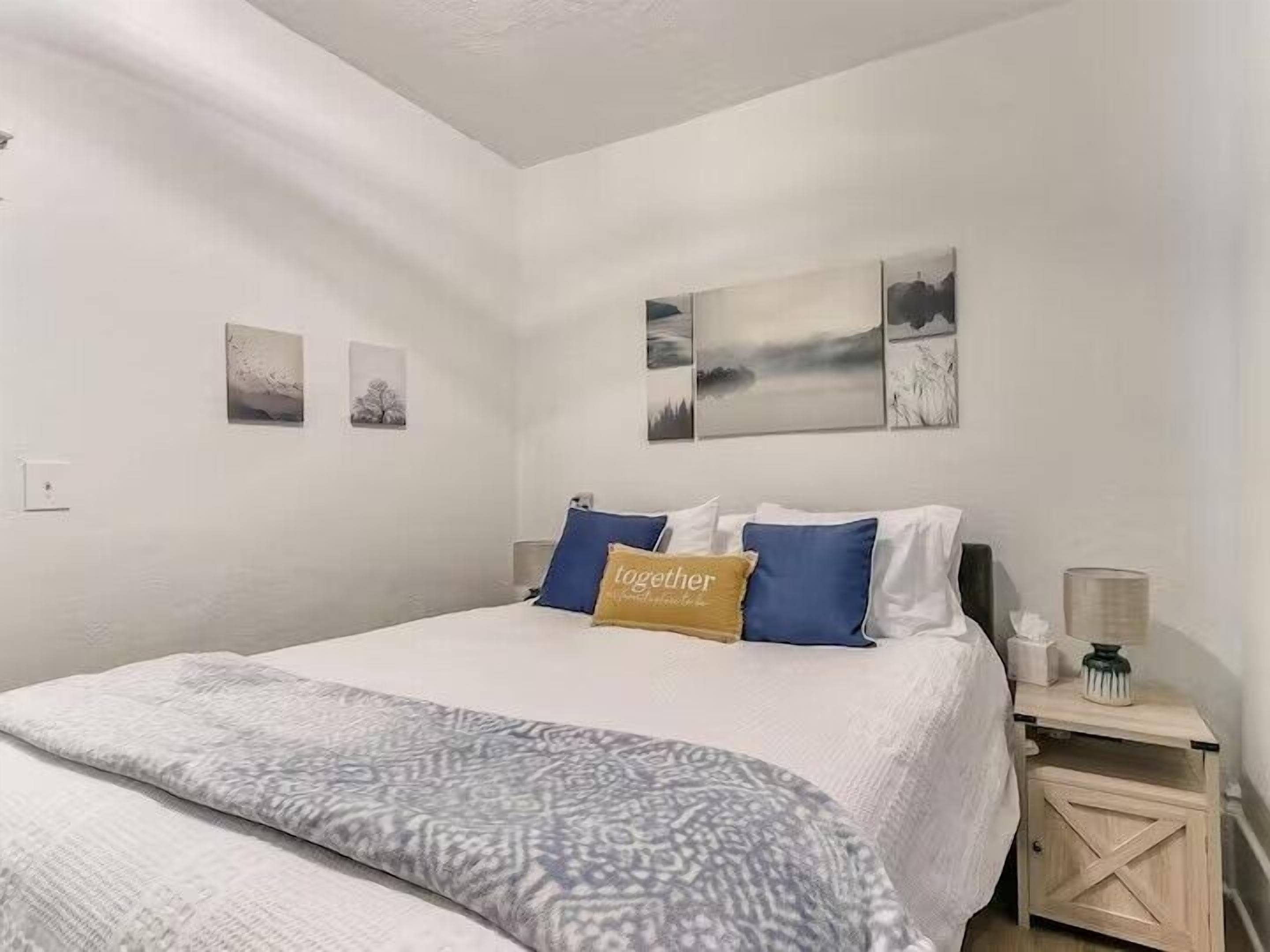 A bedroom with a bed, a nightstand, and wall art.