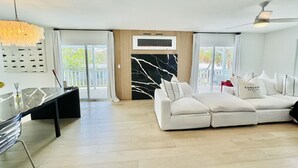 Ein modernes Wohnzimmer mit einem weißen Sofa, einem Glastisch und einem Kamin.