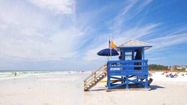 Ein Rettungsturm am Strand unter blauem Himmel.