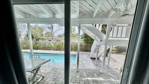 Ein überdachter Außenbereich mit Pool, Tisch und Stühlen.