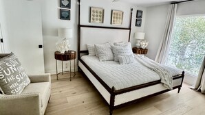 Ein Schlafzimmer mit einem großen Bett, einem Deckenventilator, einem Fenster mit Vorhängen und einem Nachttisch mit Lampe.