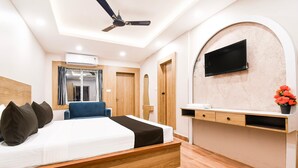 A modern bedroom with a bed, a desk, a chair, and a TV mounted on the wall. - Townhouse Shree Jagannath Puri (Puri)