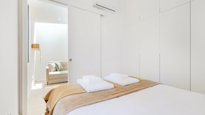 Una habitación de hotel moderna con una cama grande, un cabecero de madera y vistas a un pasillo con un sofá.