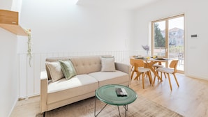 Una sala de estar moderna con un sofá, una mesa de centro de vidrio y un comedor con mesa y sillas.