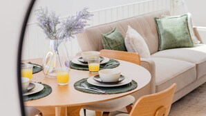 Un comedor con una mesa redonda de madera, dos sillas y un florero con flores.