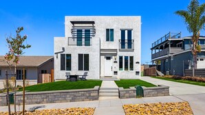 A modern two-story house with a flat roof, large windows, and a stone pathway leading to the entrance. - Coastal Ocean Beach Compound Escape (San Diego)