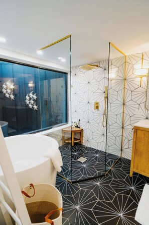 Une salle de bain moderne avec un carrelage au motif géométrique, une cabine de douche en verre et un meuble-lavabo en bois.