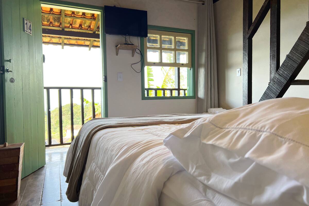 A room with a bed, a window with a view, and a balcony.