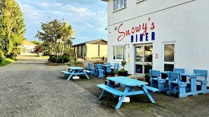 En diner, Snowy's Diner, med udendørs siddepladser og en grusvej.