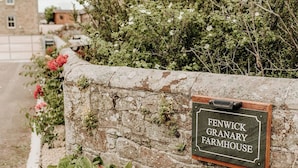 A stone wall with a sign reading "FENWICK GRANARY FARMHOUSE". - Step into thoughtfully restored accommodation a stone's throw from Holy Island (Beal)