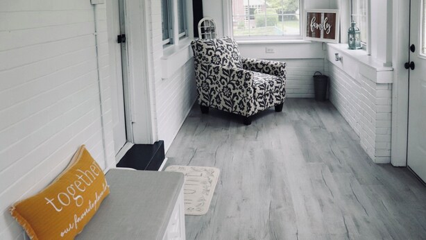 Ein gemütliches Zimmer mit einem gemusterten Sessel, einer Bank mit Kissen und einem Fenster mit Blick nach draußen.