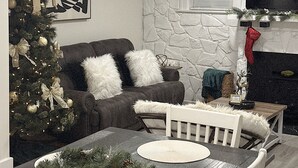 Ein modernes Wohnzimmer mit einer Steinwand, einem Kamin, einem Weihnachtsbaum und einem Essbereich mit Tisch und Stühlen.