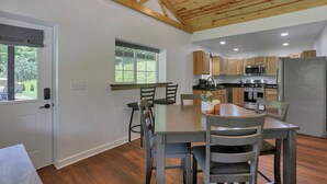 Una cocina moderna con armarios de madera, un comedor con mesa y sillas, y un techo con vigas a la vista.