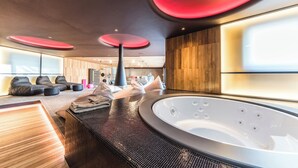 A modern spa room with a large hot tub, wooden flooring, and black seating. - Relax in this oasis This villa for exclusive use (Veneto)