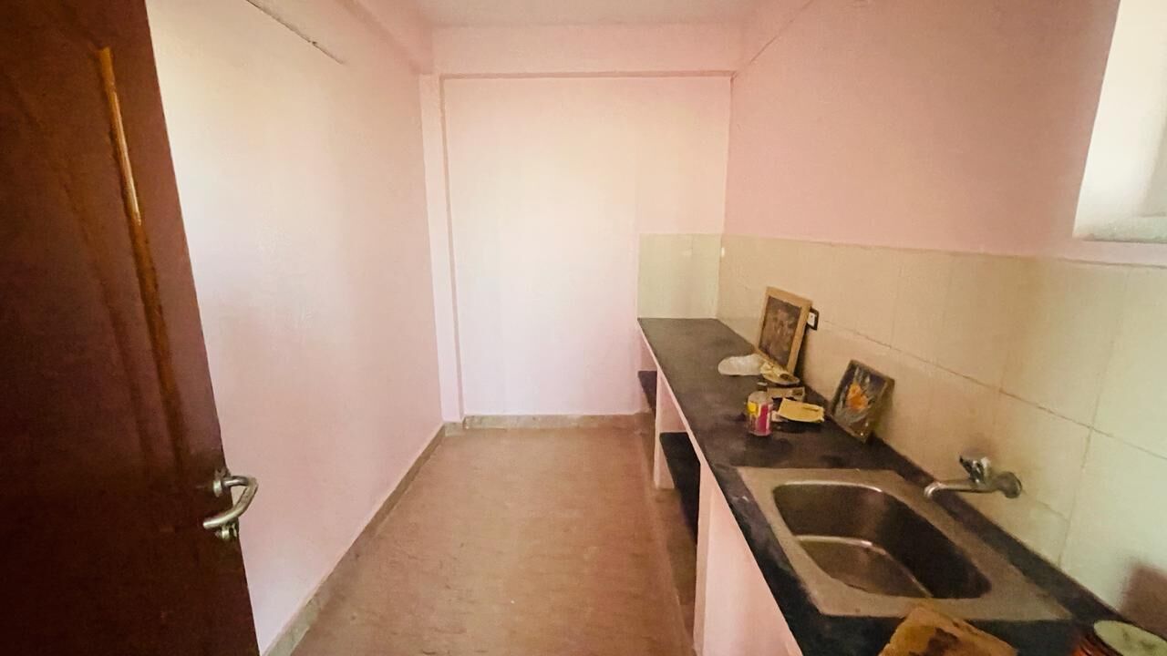 A small, narrow kitchen with a sink, a countertop, and a door.