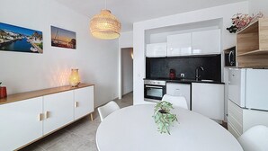 A modern kitchen with white cabinets, a black countertop, and a hanging light fixture. - GR CANAL 19 Roses / Roses - INTERimmo (Rosas / Roses)