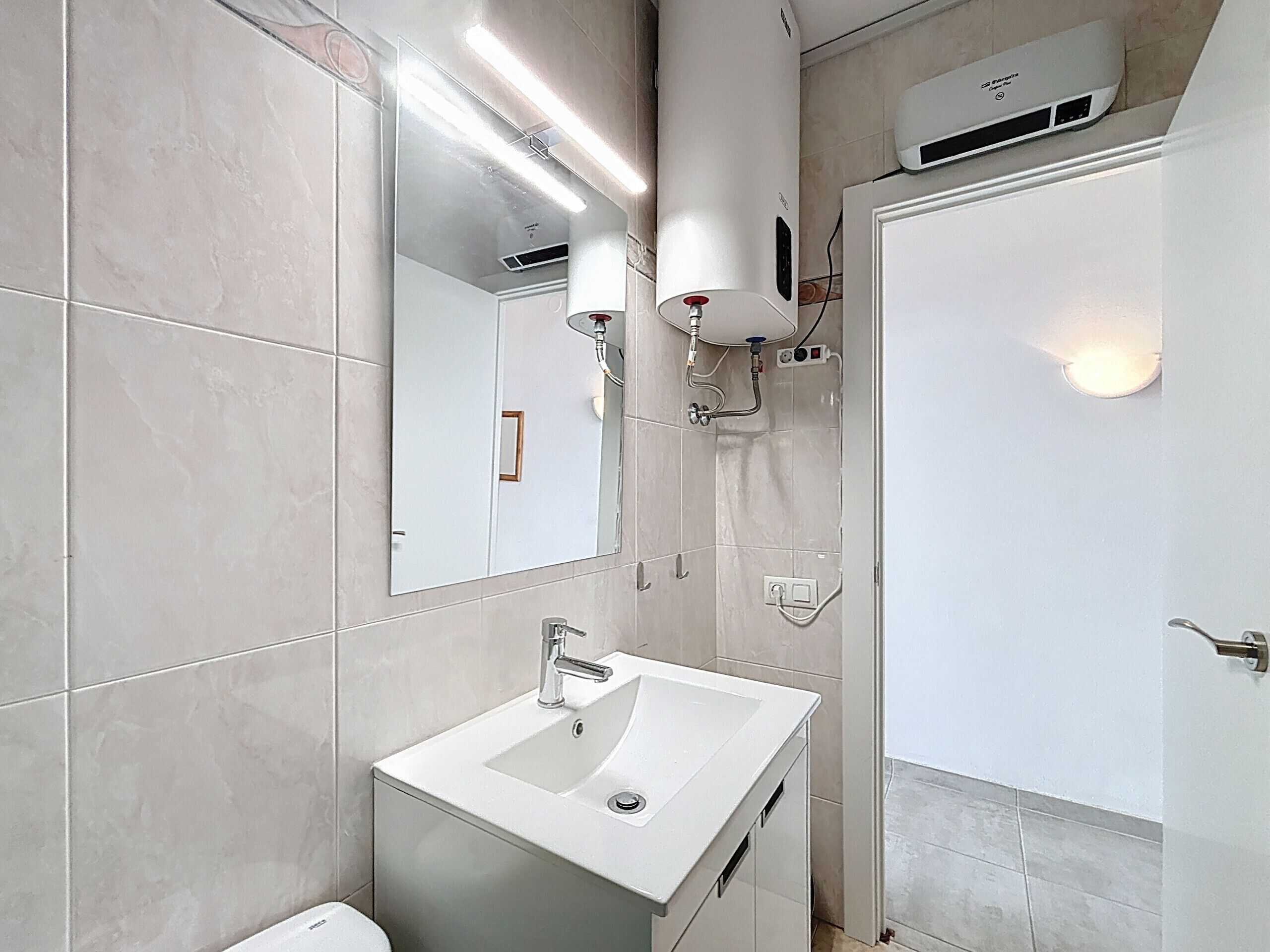 A modern bathroom with a white sink, mirror, and shower.