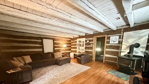 Een gezellige woonkamer met een houten vloer, een grijze bank, een klein tafeltje en een open haard.