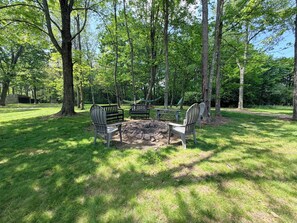 A picnic area with a fire pit, benches, and a hammock.