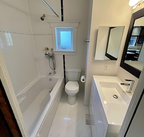 A modern bathroom with a bathtub, toilet, and sink.