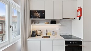 A compact kitchen with a Bosch microwave, a coffee maker, a toaster, and a sink. - GuestReady - Stylish base steps from attractions (Porto)