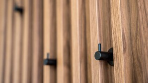 A close-up of a wooden wall with evenly spaced, dark-colored, rectangular hooks. - GuestReady - Stylish base steps from attractions (Porto)