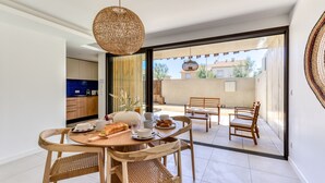A dining area with a round table, wooden chairs, and a hanging light fixture.