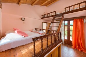 Ein Schlafzimmer mit Etagenbett, Holzboden, einer Holztreppe und einem Fenster mit Vorhängen.