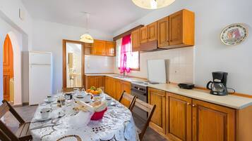 A kitchen with wooden cabinets, a dining table set with plates, glasses, and a fruit bowl.