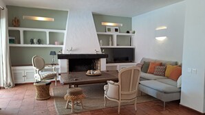 Ein Wohnzimmer mit Kamin, Fernseher, einer Couch und einem Esstisch.
