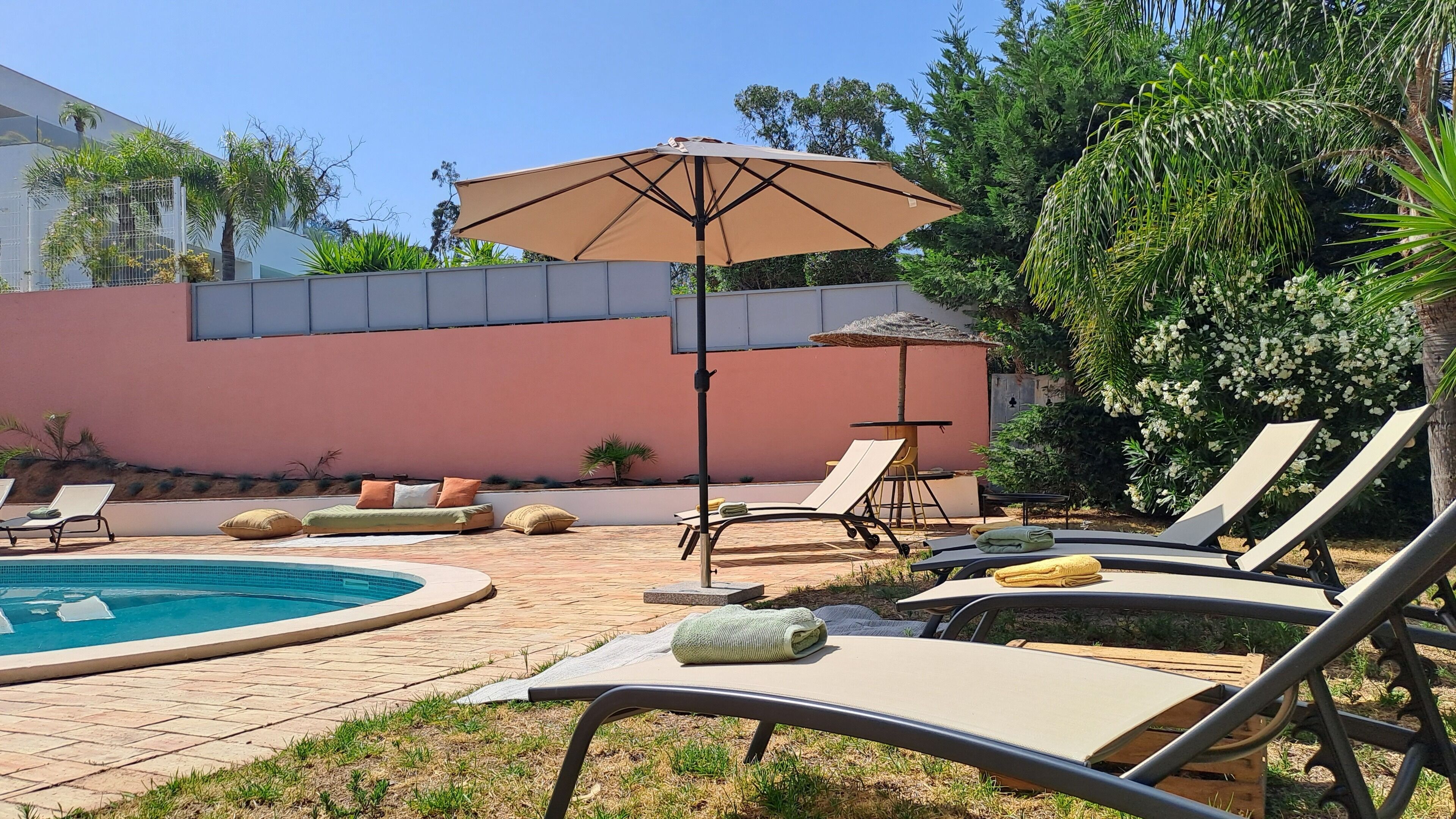 A poolside area with lounge chairs, a sun umbrella, and a small table.