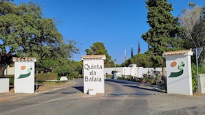Ein begrenzter Eingangsbereich mit einem Schild, das 'Quinta da Balia' zeigt, und ein Empfangsbereich mit Flaggen.