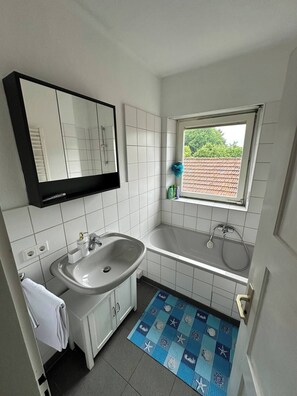 Un baño pequeño con lavamanos, espejo y ventana.