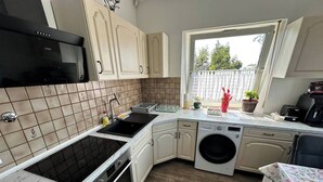 A compact kitchen with a built-in stove, a washing machine, and a window providing natural light.
