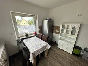 Una pequeña cocina con una mesa de comedor, un refrigerador y un armario.