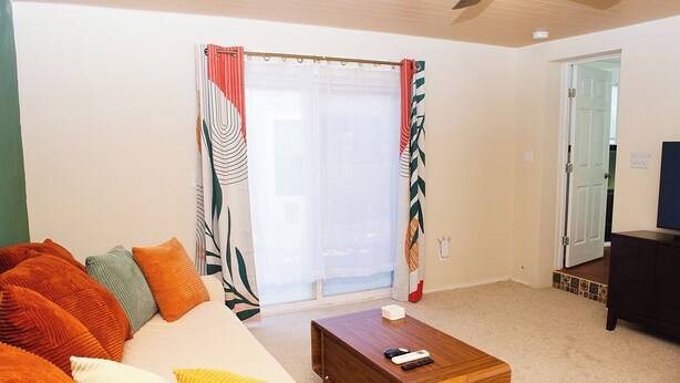 A living room with a sofa, coffee table, and a door leading to another room.