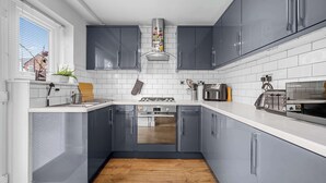 Una cocina moderna con armarios grises, encimeras blancas, una campana extractora de acero inoxidable y un horno empotrado.