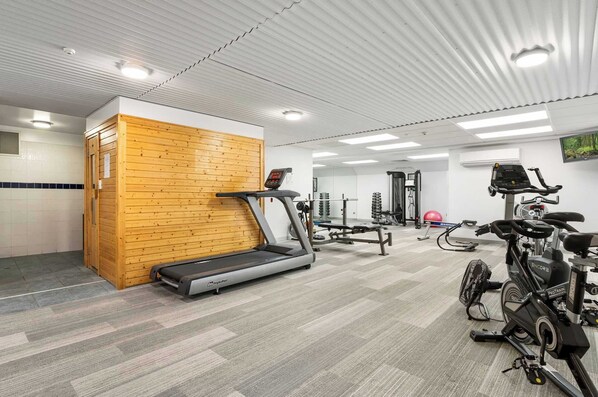 A gym with a treadmill, stationary bikes, and weight machines.