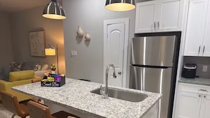 Una cocina moderna con encimera de granito, electrodomésticos de acero inoxidable y una barra con taburetes.