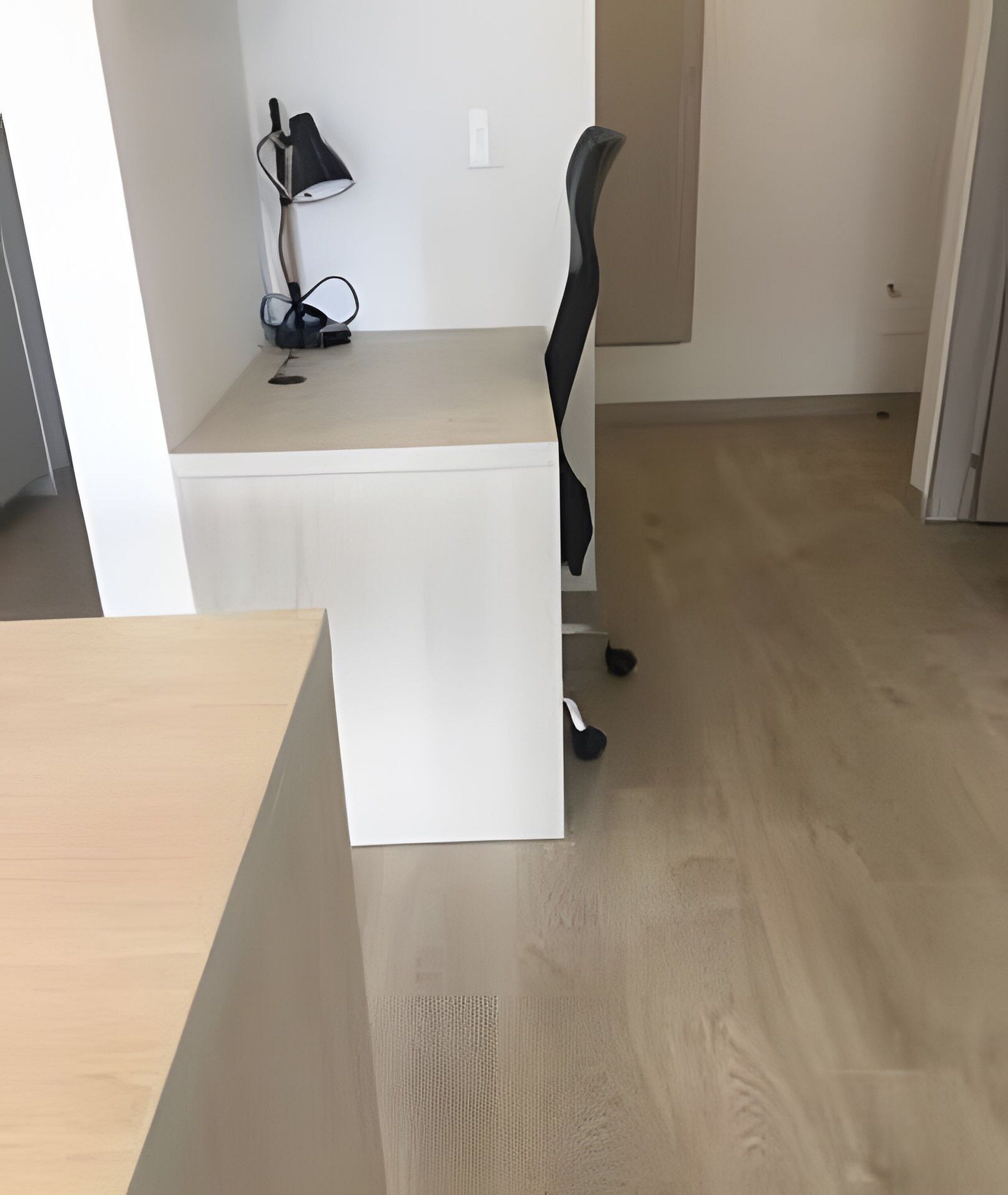 Un espacio de oficina moderno con un escritorio blanco, una silla de oficina negra y una lámpara.