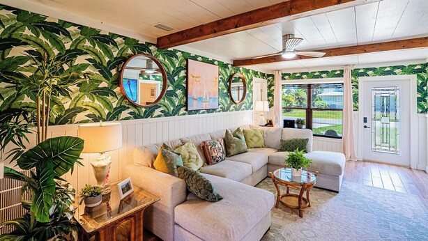A living room with a sectional sofa, a round coffee table, and a large window with a view of greenery. - Waterfront Oasis with Boat Lift & Hot Tub in Bokeelia (Bokeelia)