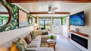 A living room with a sectional sofa, a TV mounted on the wall, a fireplace, and a ceiling fan. - Waterfront Oasis with Boat Lift & Hot Tub in Bokeelia (Bokeelia)