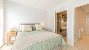 A bedroom with a bed, bedside tables, a nightstand, a bathroom with a shower, a sink, and a mirror. - Modern 4BR New Home near Biz Park & Station | Pass the Keys (Reading)