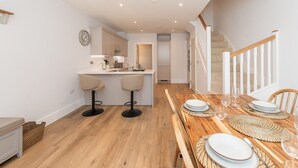 A modern kitchen with white cabinets, a wooden countertop, and two bar stools. - Modern 4BR New Home near Biz Park & Station | Pass the Keys (Reading)