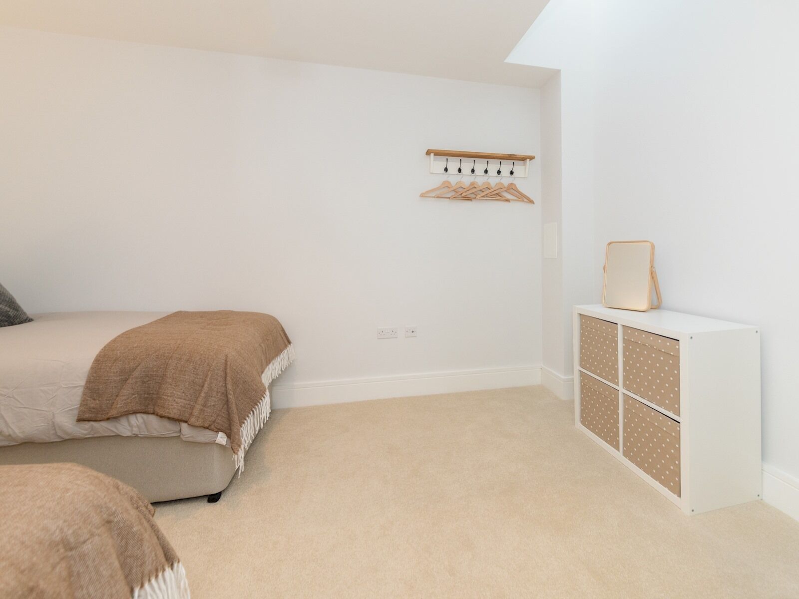 Un dormitorio con cama, cómoda y perchero.