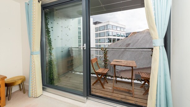 A balcony with a glass door, a wooden table, and a chair. - Stylish Central 1-Bed Flat with Private Balcony | Pass the Keys (Reading)