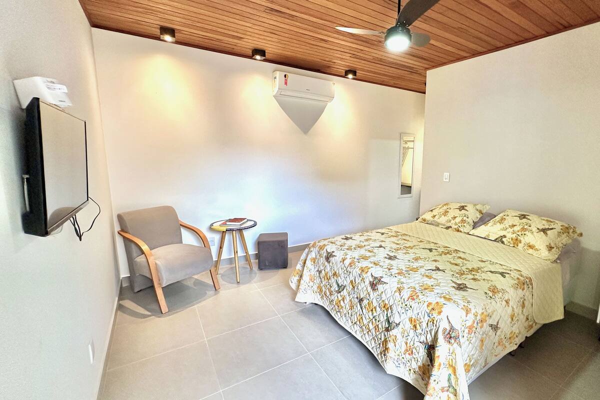 Een slaapkamer met een bed, een stoel, een klein tafeltje en een nachtkastje.