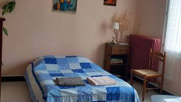 Ein Schlafzimmer mit einem Bett, einem Sessel, einem Heizkörper, einer Lampe und Wanddekorationen.