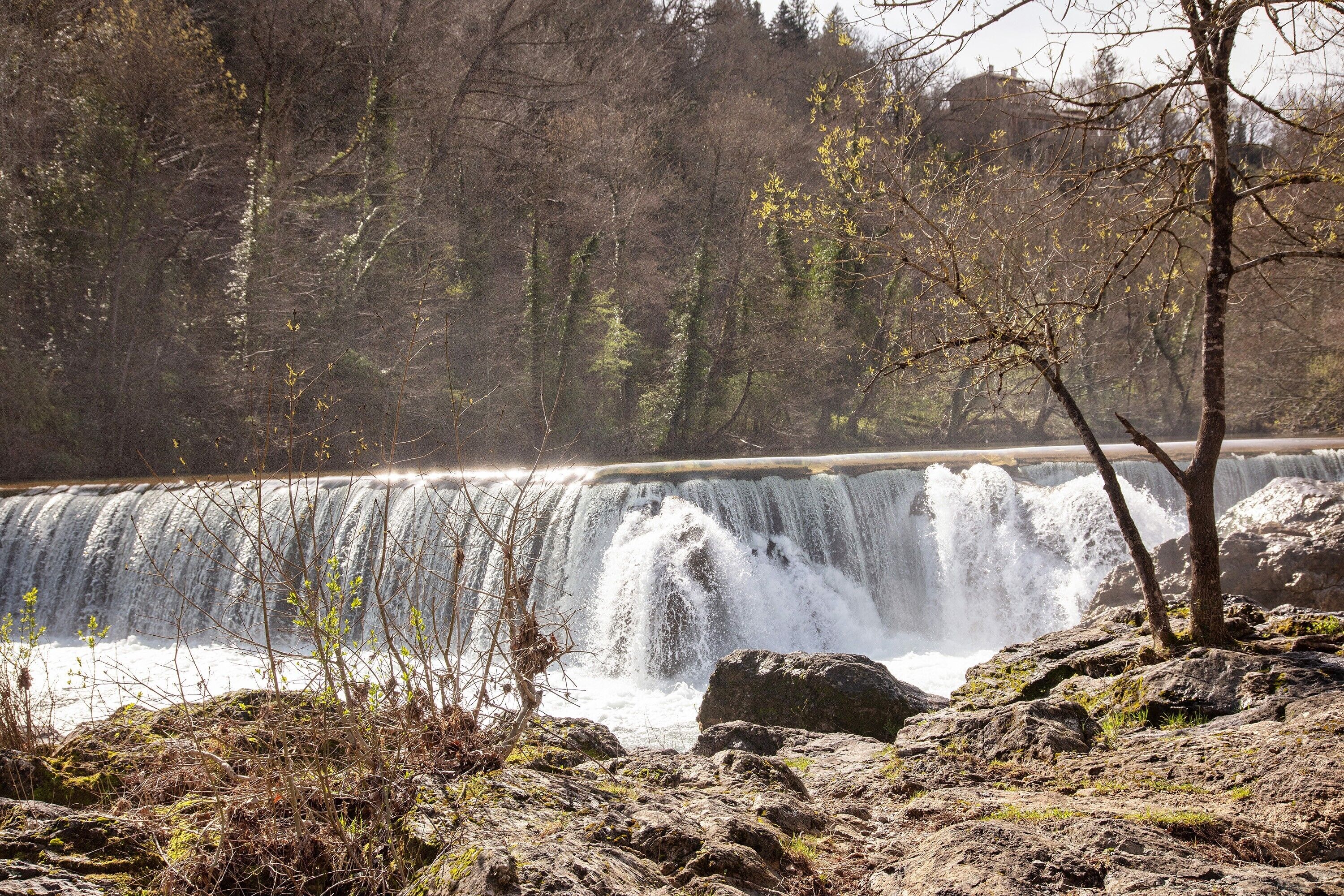 Une cascade entourée d’un paysage rocheux et d’une végétation clairsemée.