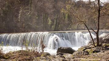 Une cascade entourée d’un paysage rocheux et d’une végétation clairsemée.